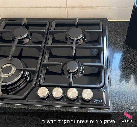 כיריים גז שחורות עם כפתורים כסופים במטבח מודרני